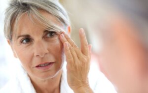 Older lady checking her face in the mirror after cheek fillers